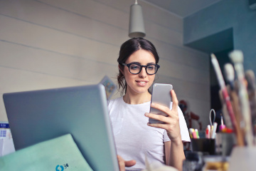 Eine Kundenberaterin sitz vor dem Laptop und telefoniert mit einem Kunden